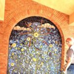 Author studies ceramic mosaic of sun, sky, clouds and flowers at Albuquerque Academy in New Mexico