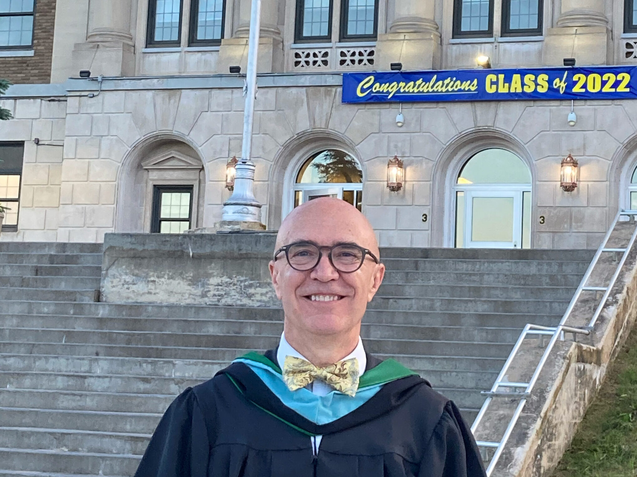 In graduation gown in front of school.